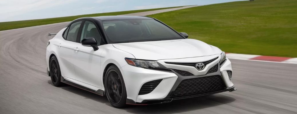 One white color 2023 Toyota Camry Hybrid is running on the road.