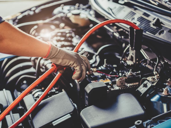 Technician connecting jumper cables during vehicle battery service